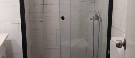 Ein Badezimmer mit einer Duschkabine, einer weißen Toilette und einem weißen Waschbecken.