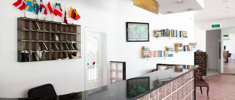 A reception area with a marble counter, a bookshelf with books, and a wall with flags.