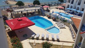 A rooftop pool area with lounge chairs, umbrellas, and a view of the beach. - One More Day Hotel (Bodrum)