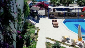 A hotel with a pool, outdoor seating, and a view of the sea.