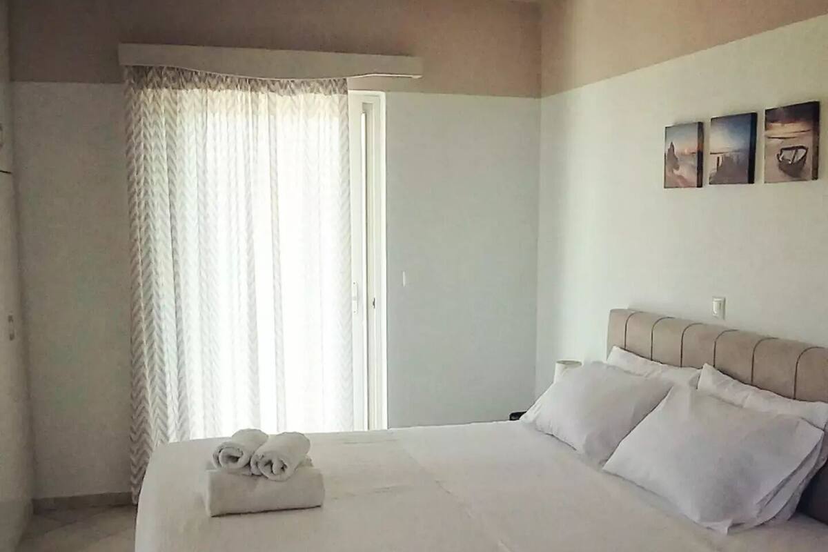 A hotel room with a large bed, a window with curtains, and a wall with three pictures.