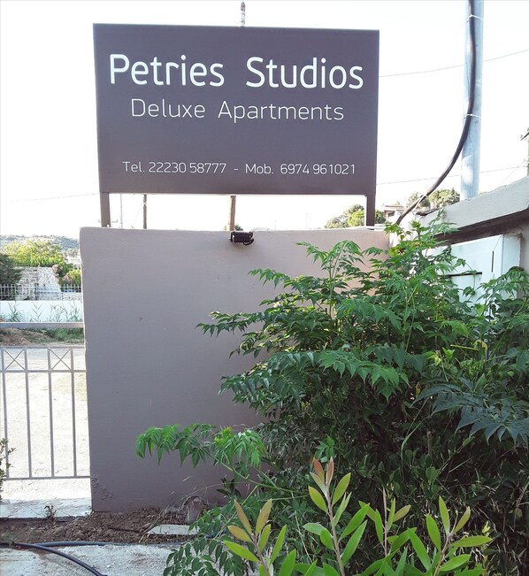 A sign for Pétries Studios Deluxe Apartments with contact numbers. - Petries Studios (Kymi-Aliveri)