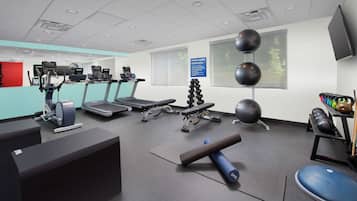 A fitness center with treadmills, elliptical machines, a yoga mat, and exercise balls.