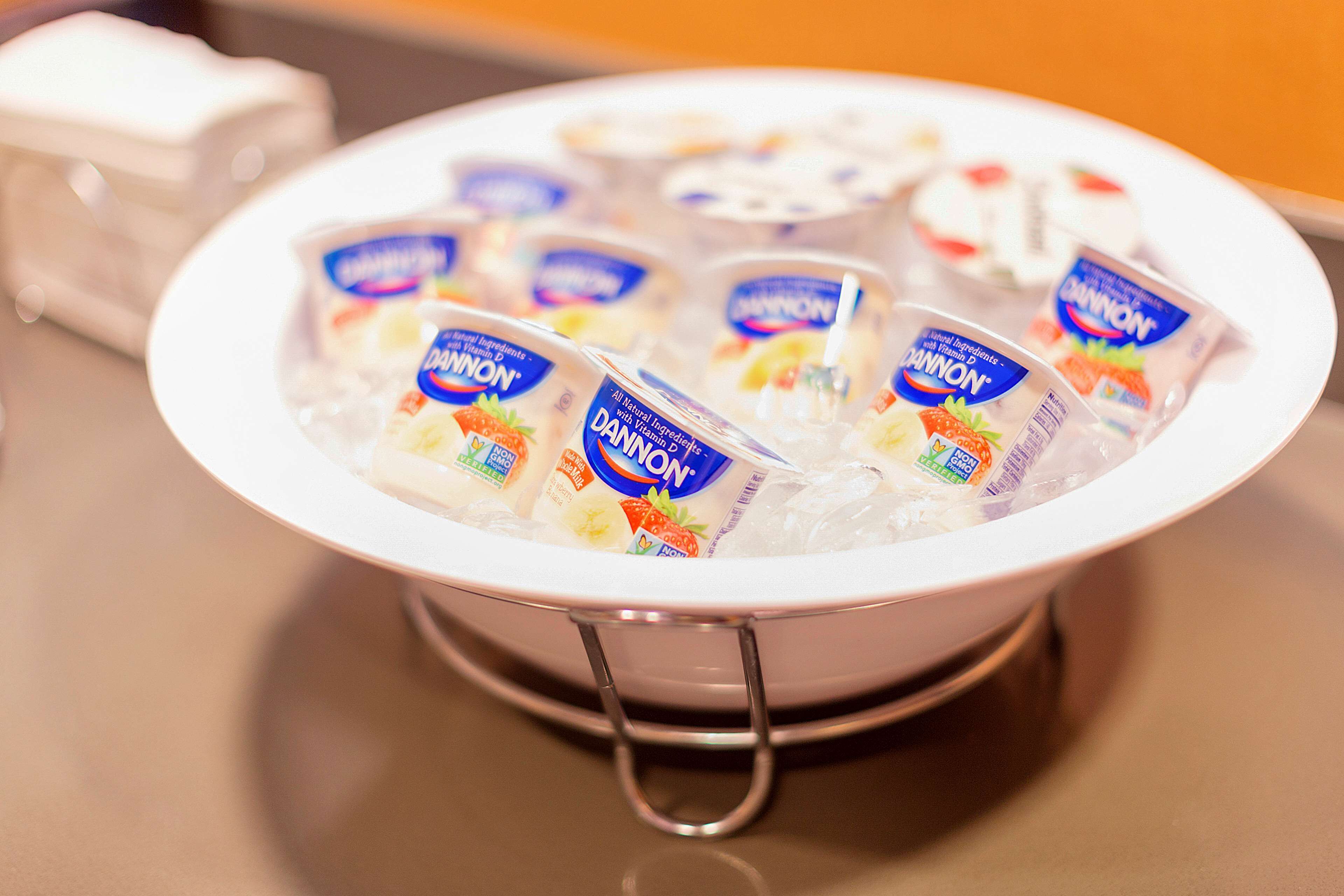 A white bowl filled with ice and several packets of DANON yogurt.