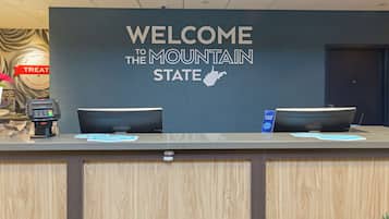 Un mostrador de recepción con un cartel que dice "WELCOME TO THE MOUNTAIN STATE" y el contorno del estado.