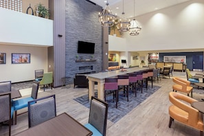 Un moderno vestíbulo de hotel con zona de bar, asientos y un televisor montado en la pared.