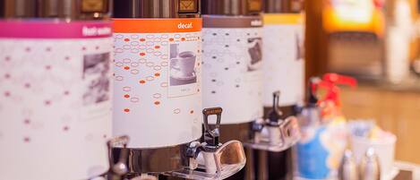 En rad kaffedispensrar med hexagonala mönster och en etikett med texten ”decaf”, vilket visar att det är en kaffestation på ett hotell.