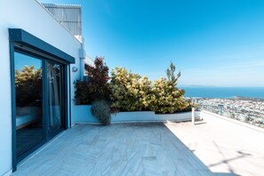 Un balcon moderne offrant une vue dégagée sur la mer et sur le paysage urbain au loin.