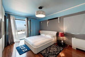 Une chambre moderne avec un grand lit, une vue sur la mer et une lampe rouge.