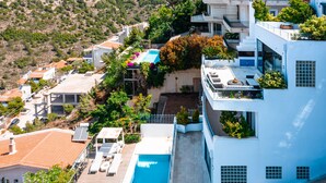 A modern building with a rooftop pool, multiple balconies, and a view of the surrounding landscape. - Villa Azure (Vari-Voula-Vouliagmeni)