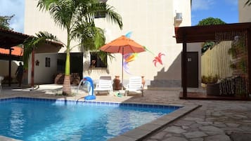 Piscina com palmeira e uma estátua de flamingo decorativo.
