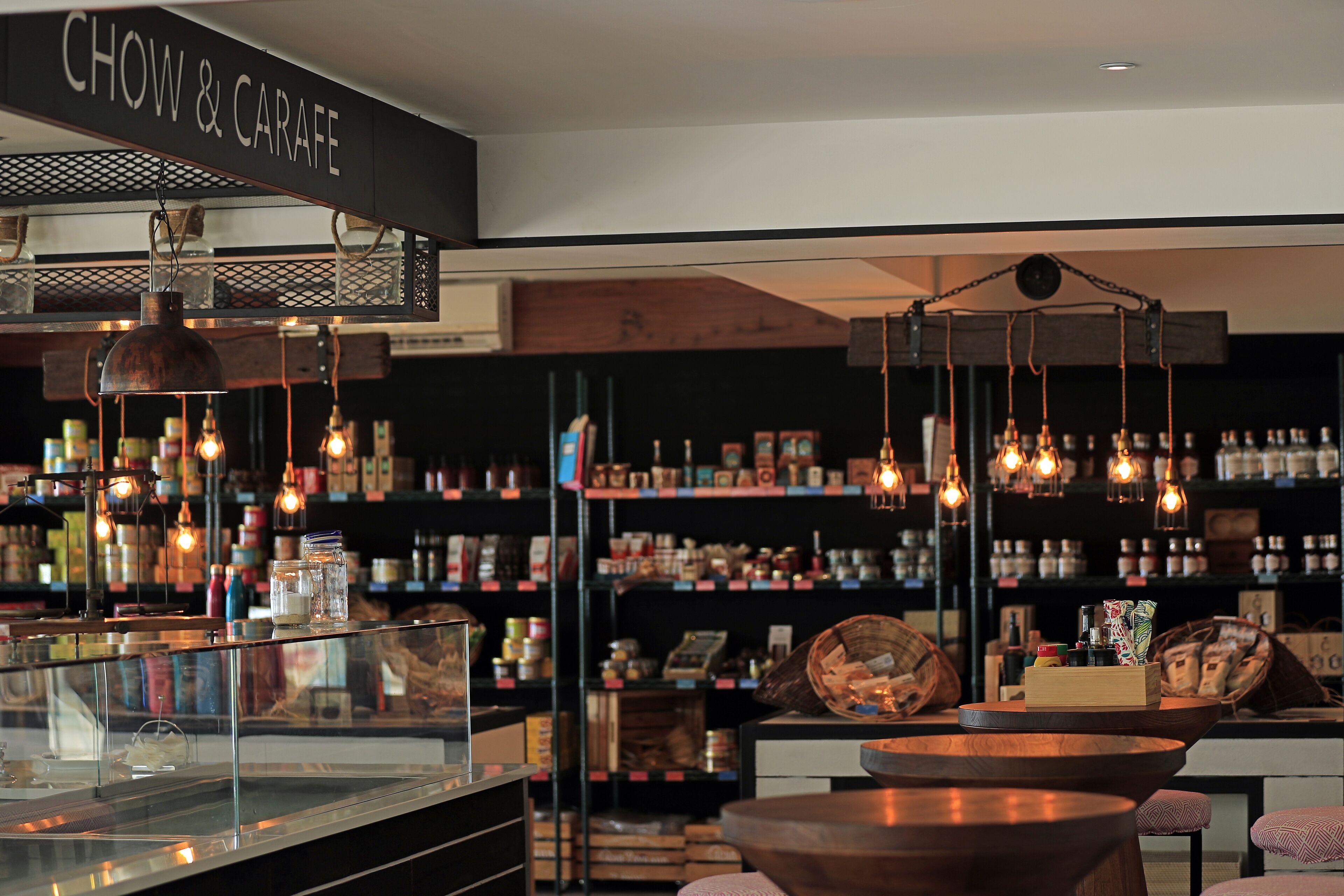 A restaurant interior with exposed brick walls, hanging pendant lights, and a variety of jars and containers on shelves.