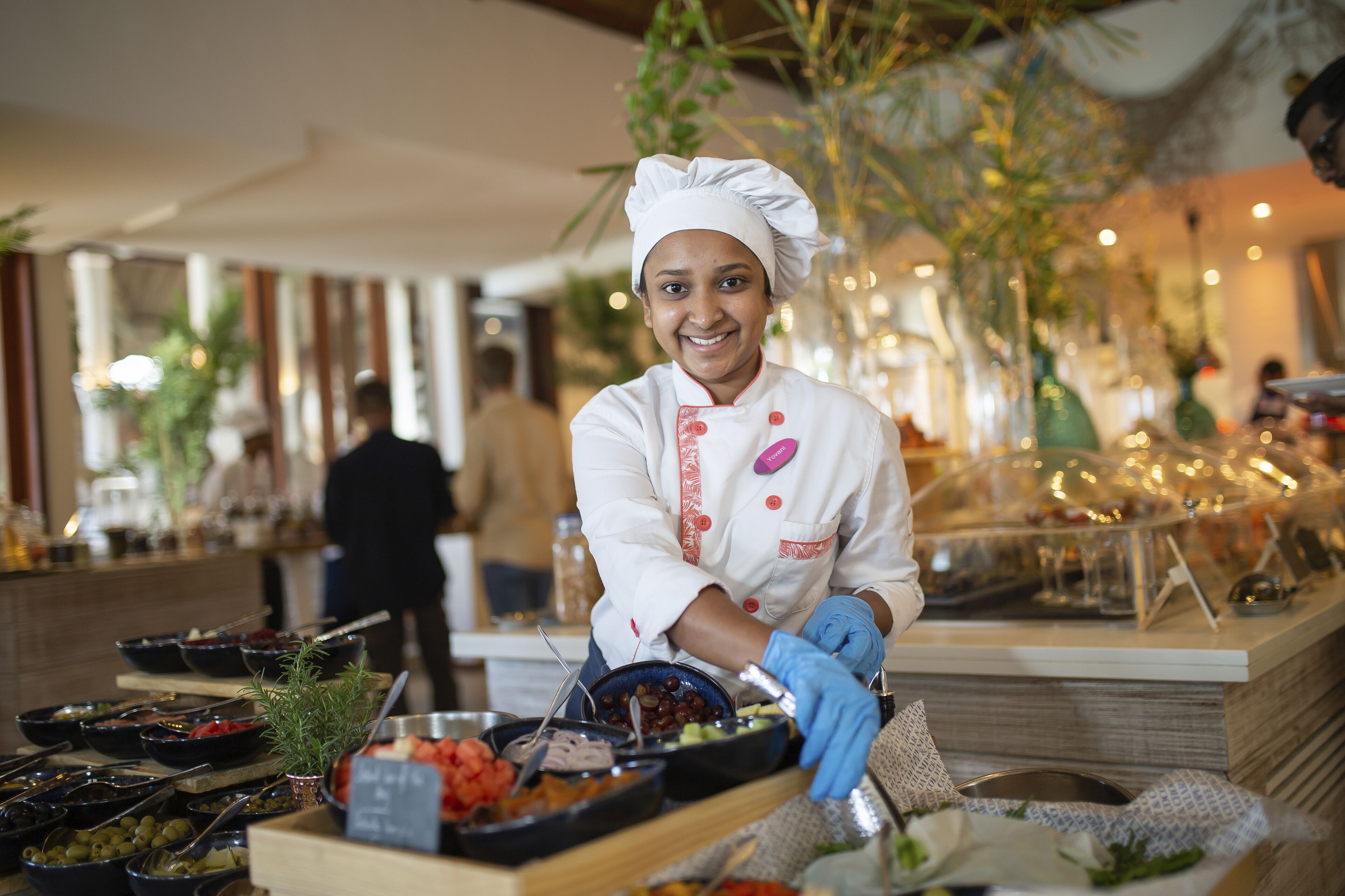 Montaje de bufé con diversos platos y un chef con uniforme.