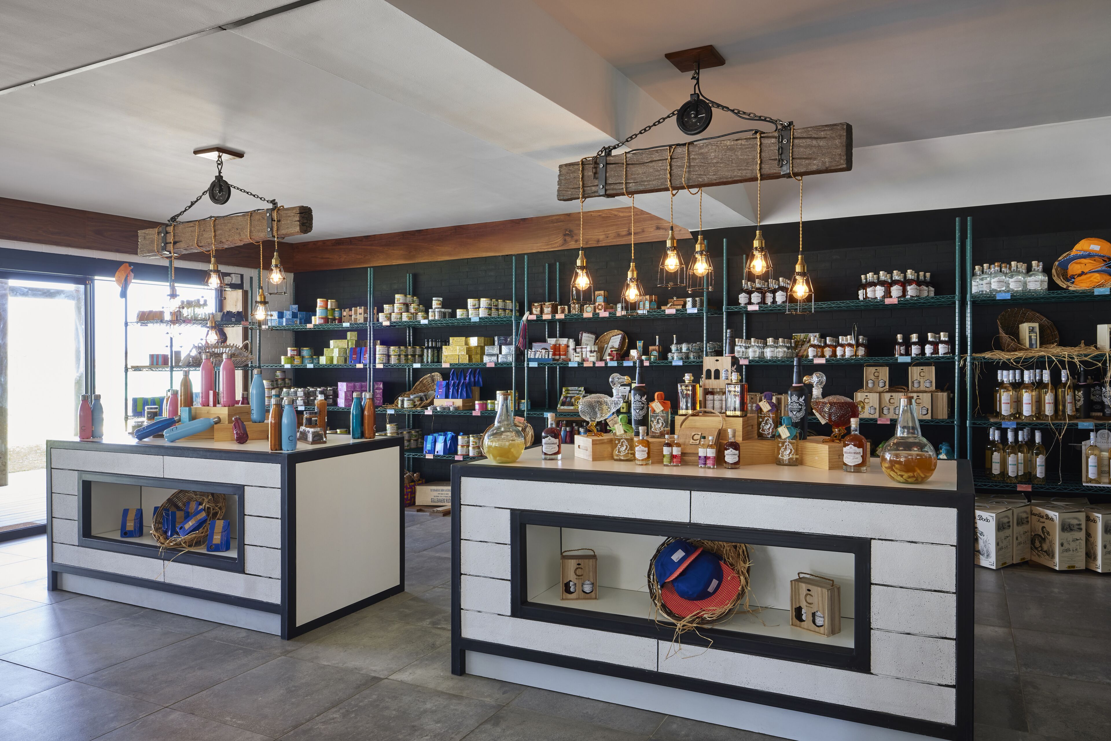 Eine Bar mit zwei Tresen, Regalen voller Flaschen und hängenden Lampen.