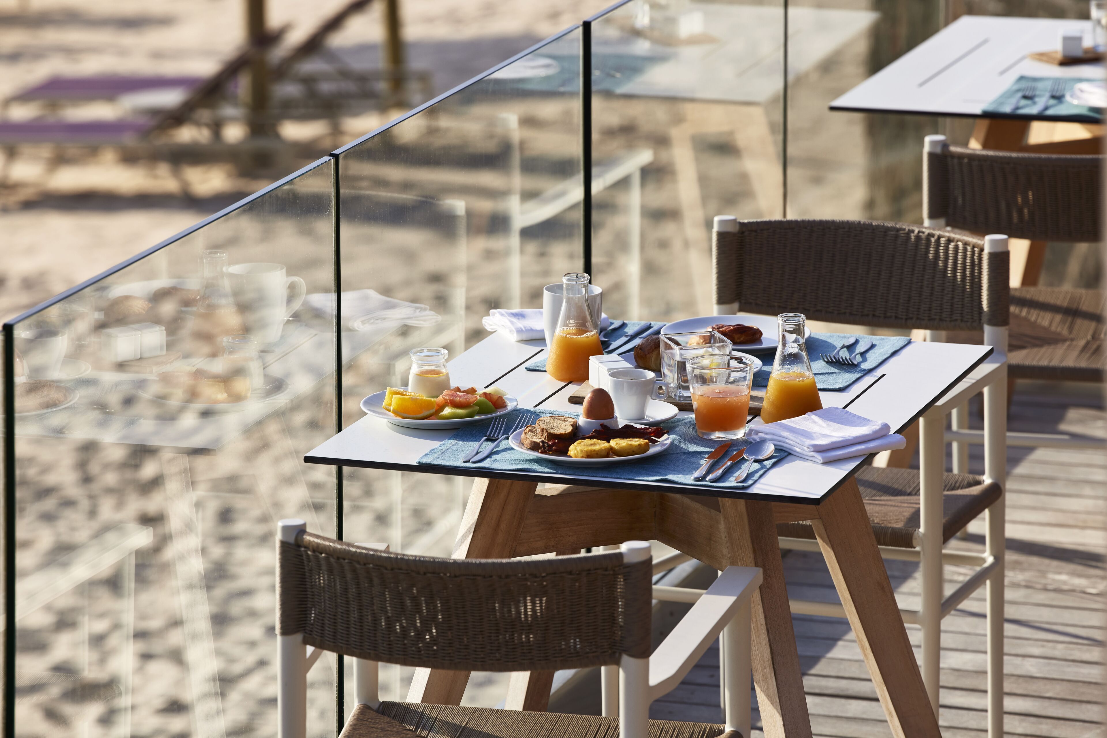 Une table de petit-déjeuner avec des assiettes remplies de nourriture, un verre de jus d’orange et une bouteille de jus.