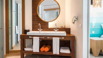 Un baño moderno con tocador de madera, un espejo redondo e lavamanos doble.