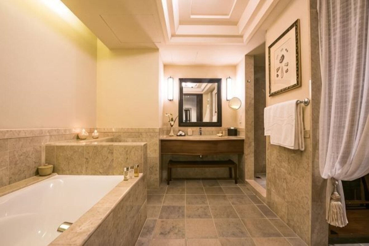 Un baño con bañera, tocador, espejo y toallero.