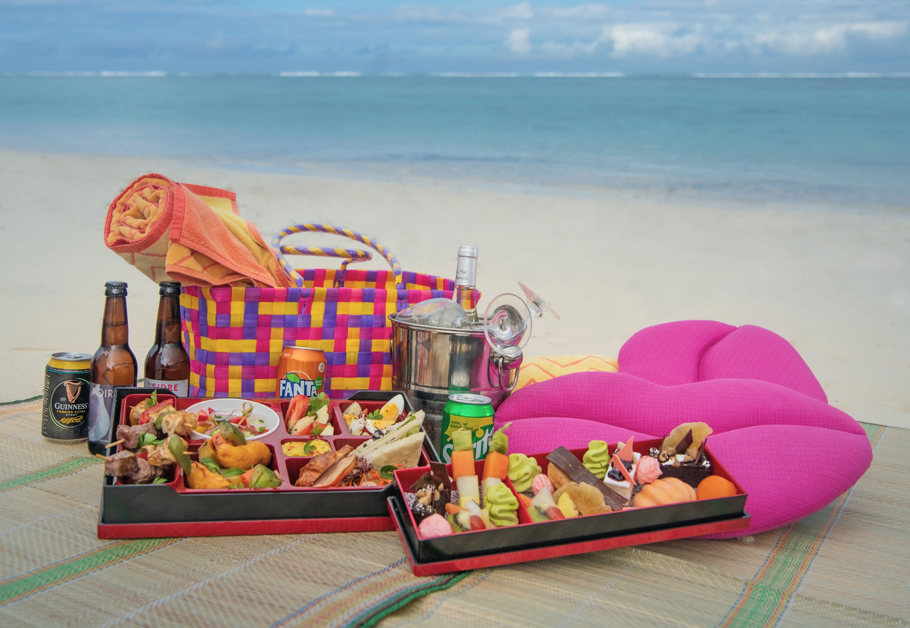 A beach picnic setup with food, drinks, and a portable stove.