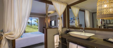 A hotel room with a bed, a large mirror, a bathroom with a sink, and curtains.