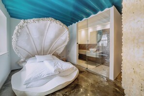 Un dormitorio moderno con una cama curva distintiva, una pared de vidrio y un techo azul.