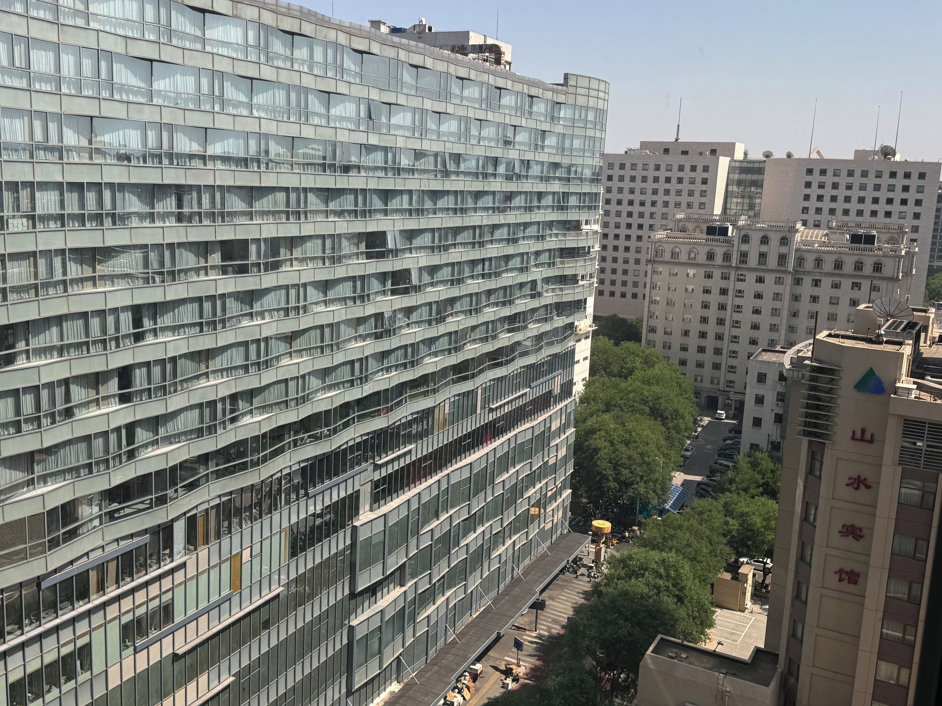 Un immeuble moderne de grande hauteur, doté d’une façade en verre, de nombreux étages et d’un espace sur le toit bien visible.