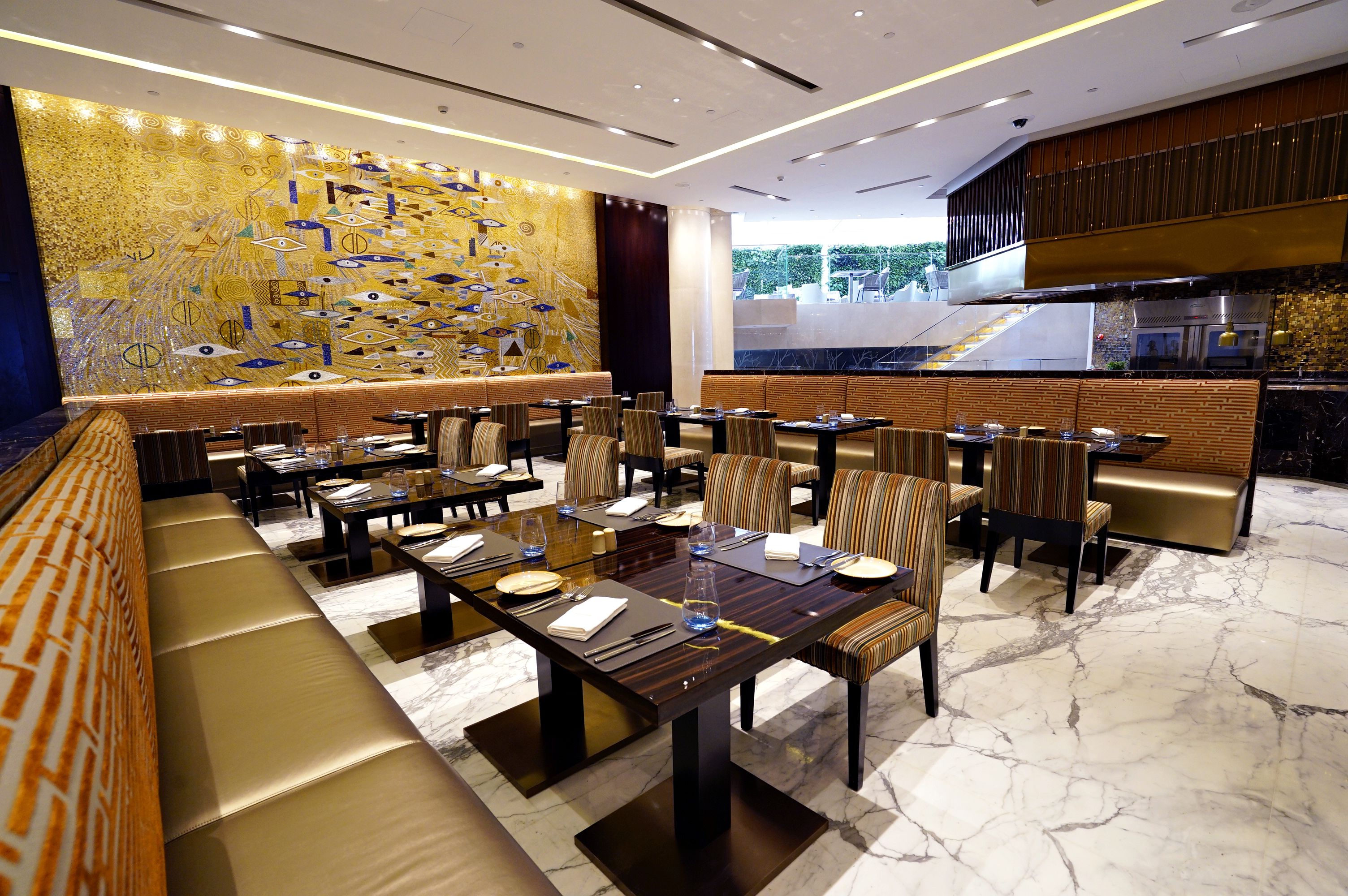 Un restaurant moderne doté d’une longue table conviviale, de petits espaces individuels et d’une fresque murale décorative.