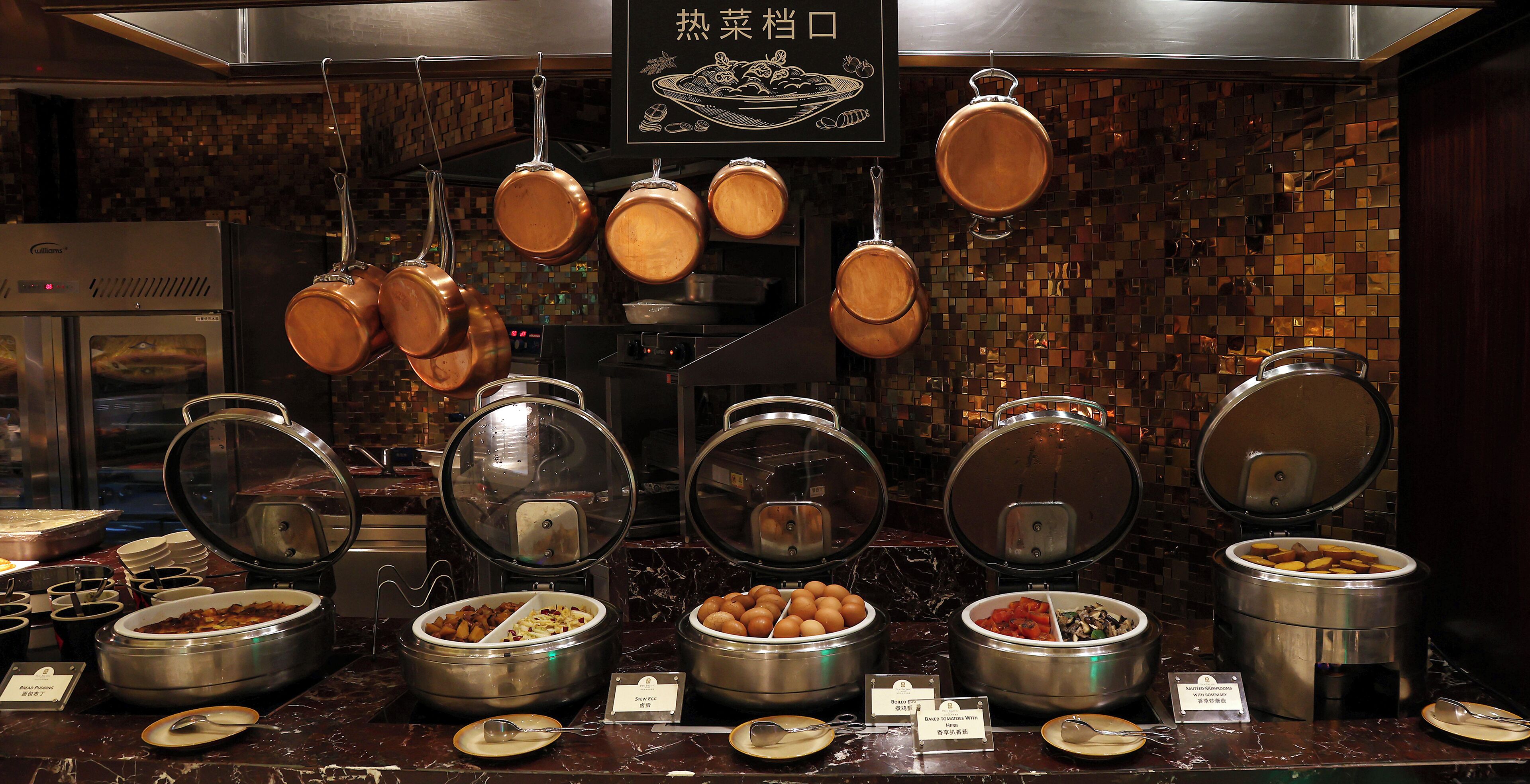 A buffet setup with various food containers and utensils.