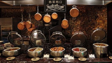 A buffet setup with various food containers and utensils.