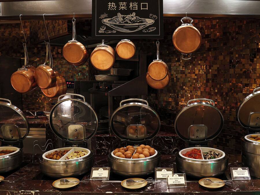 A buffet setup with various food containers and utensils.