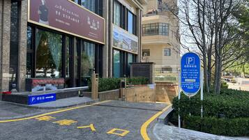 A building with a large signboard, a parking sign, and a clear pathway leading to the entrance.