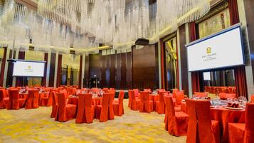 A banquet hall with tables set for a formal event, featuring a large screen displaying the hotel's name.