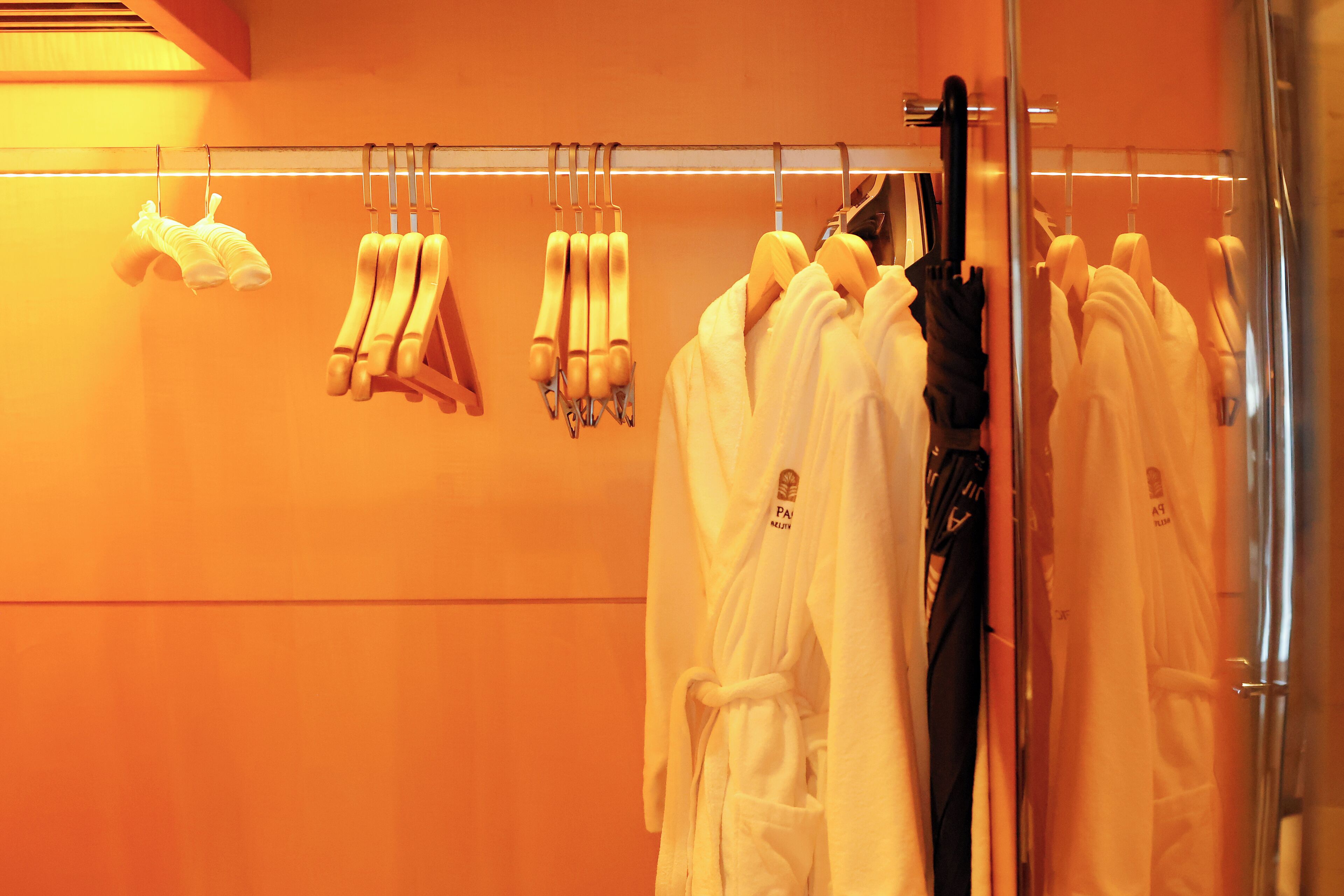 A hotel room with a bathroom featuring a towel rack with multiple towels and robes hanging.