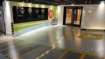 A hotel lobby with a reception desk, a sign for the elevator, and a handicapped parking space.