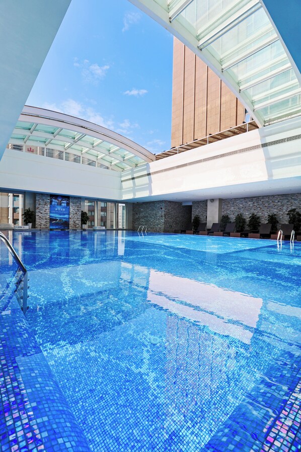 An indoor swimming pool with clear blue water, surrounded by a modern architectural design with glass and stone elements.
