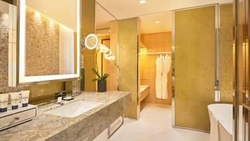 Un baño moderno con lavamanos de mármol, un espejo grande, un perchero para bata y una orquídea en maceta.