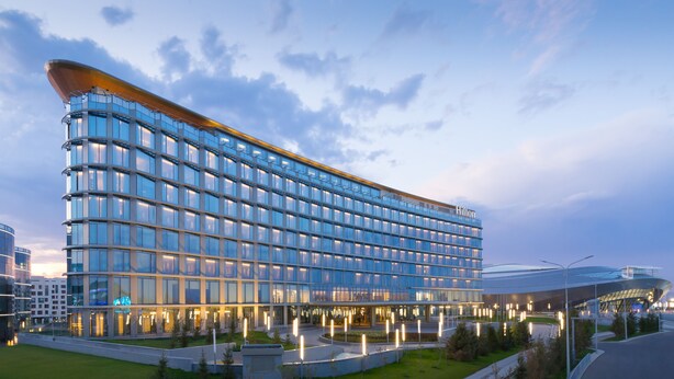 Un hotel moderno con fachada curva, amplias ventanas y un área de entrada bien iluminada.