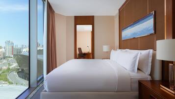 Quarto de hotel com uma cama grande, uma escrivaninha, uma cadeira, um abajur e um quadro na parede.