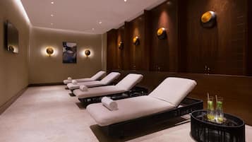 Une salle de spa équipée de fauteuils inclinables, d’une table de massage et d’un système d’éclairage mural.