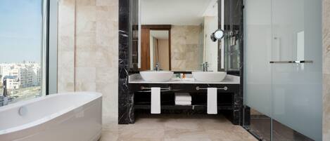 A modern bathroom with a bathtub, two sinks, a large mirror, and a glass shower enclosure.
