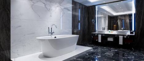 A modern bathroom with a freestanding bathtub, two sinks, and a large mirror.