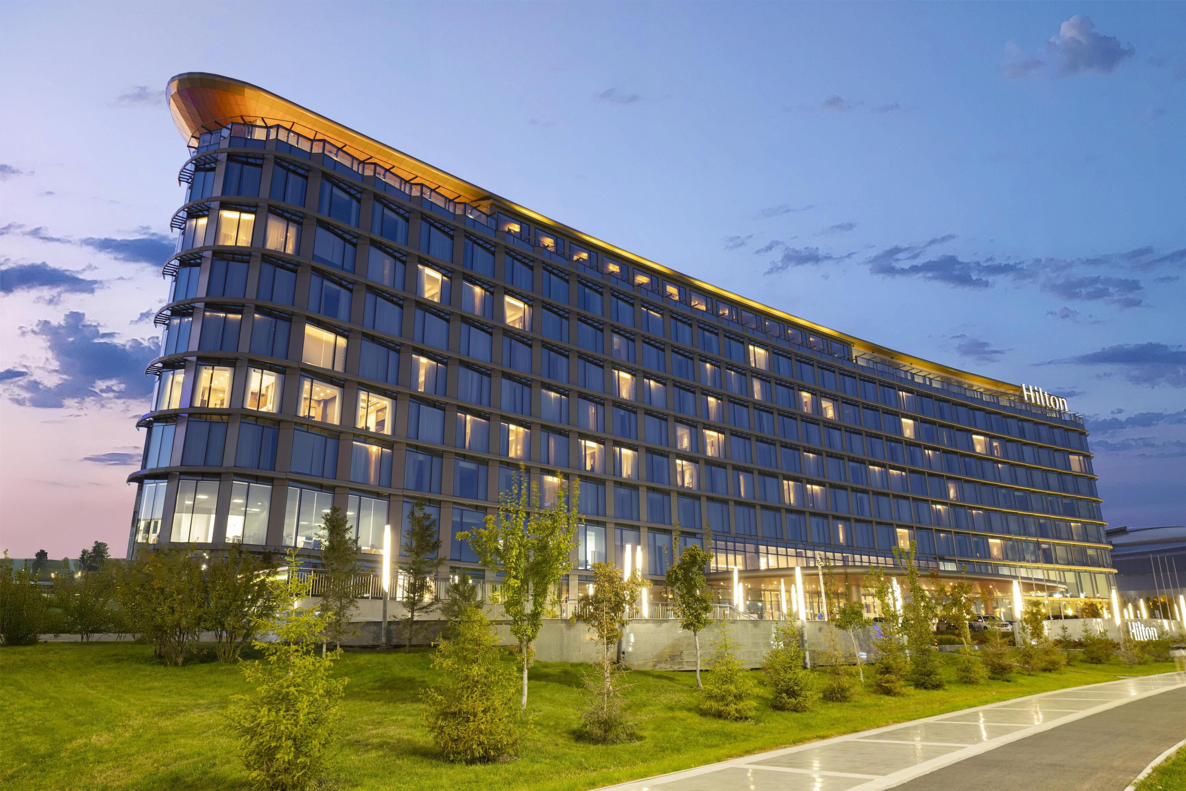 Ein modernes Hotelgebäude mit mehreren Etagen und einem gewölbten Dach.