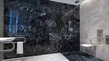 Ein modernes Badezimmer mit schwarzem Marmor an der Wand, einem weißen Waschbecken und einer Duschkabine.
