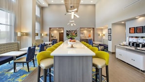 Uma área de refeições de hotel moderna com uma ilha central, cadeiras altas e bancada de cozinha.