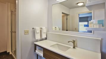 Un baño con lavamanos blanco, un espejo y una puerta de ducha de vidrio.