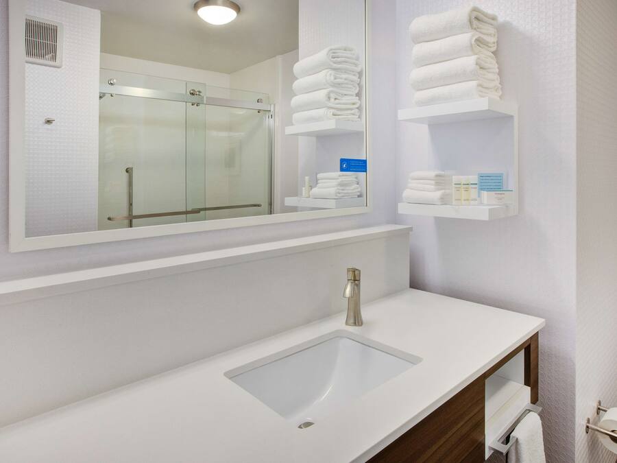 A modern bathroom with a glass shower, white sink, and towel storage.