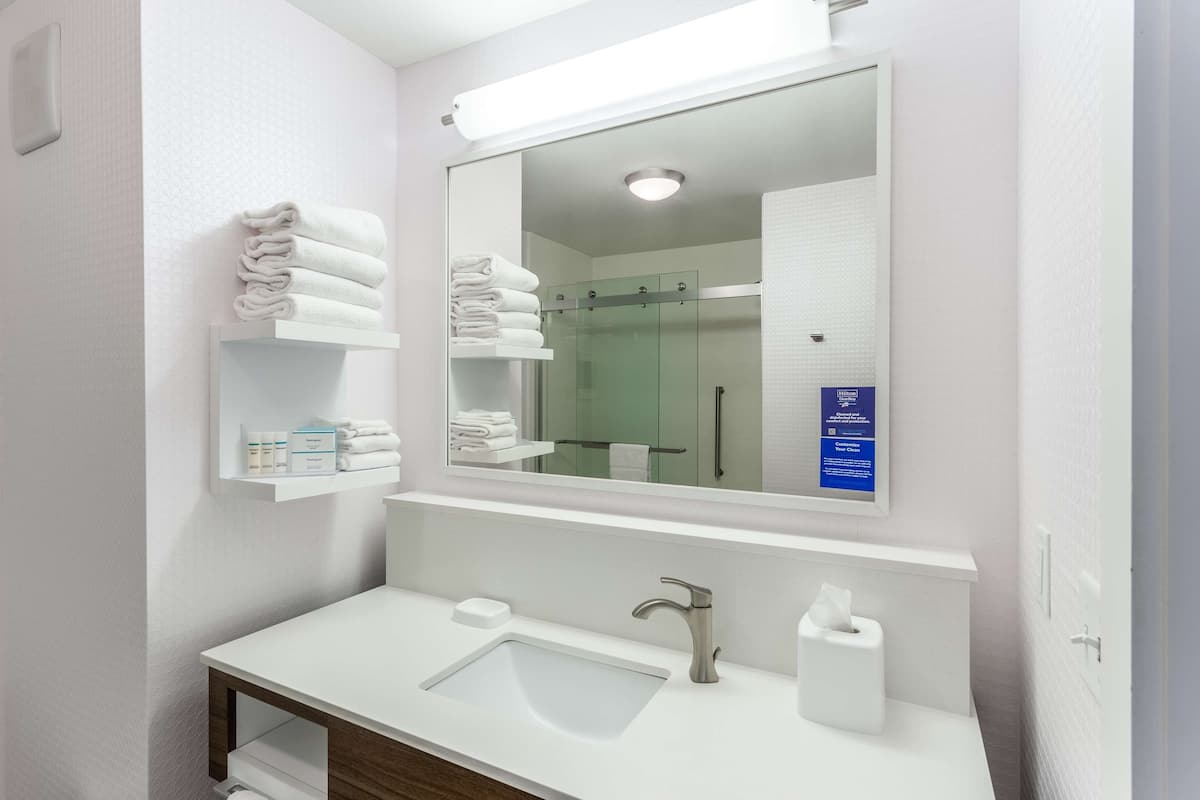 A modern bathroom with a white sink, a mirror, and a glass shower enclosure.