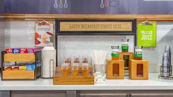 A breakfast bar with cereal, juice, and yogurt options.