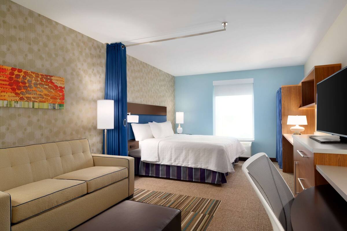 Une chambre d’hôtel avec un lit, un canapé, un bureau et une télévision.