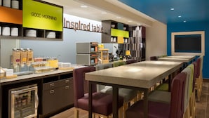 A modern breakfast area with a long communal table, individual seating, and a variety of breakfast options.