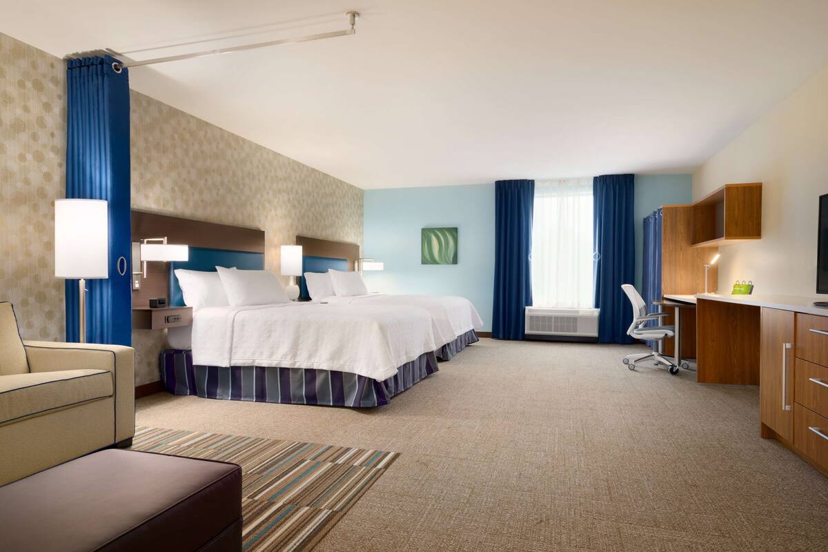 Une chambre d’hôtel avec un grand lit, un bureau, une chaise, un canapé et un téléviseur.